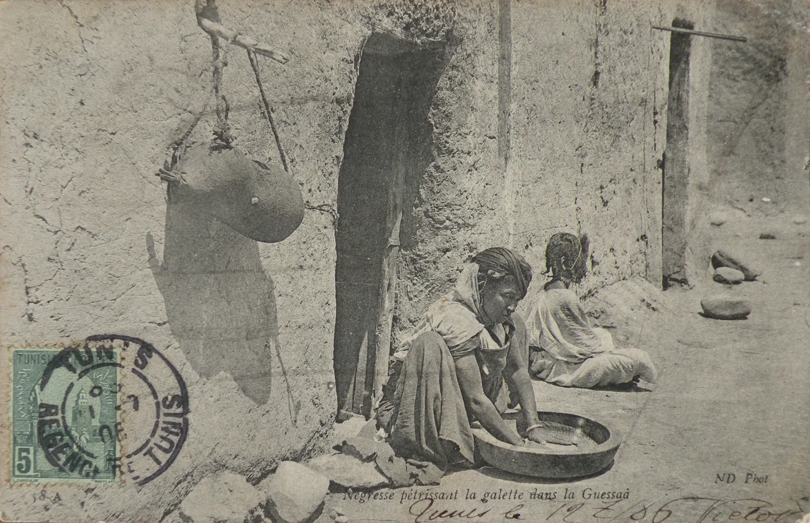 Historical 1906 postcard by Neurdein (ND Phot) showing a woman working semolina in a guessaa (flat clay bowl) in Algeria — documenting the traditional hand-rolling technique central to the couscous knowledge practices inscribed by Algeria, Mauritania, Morocco, and Tunisia on UNESCO's Representative List as Intangible Cultural Heritage File 01602 in December 2020