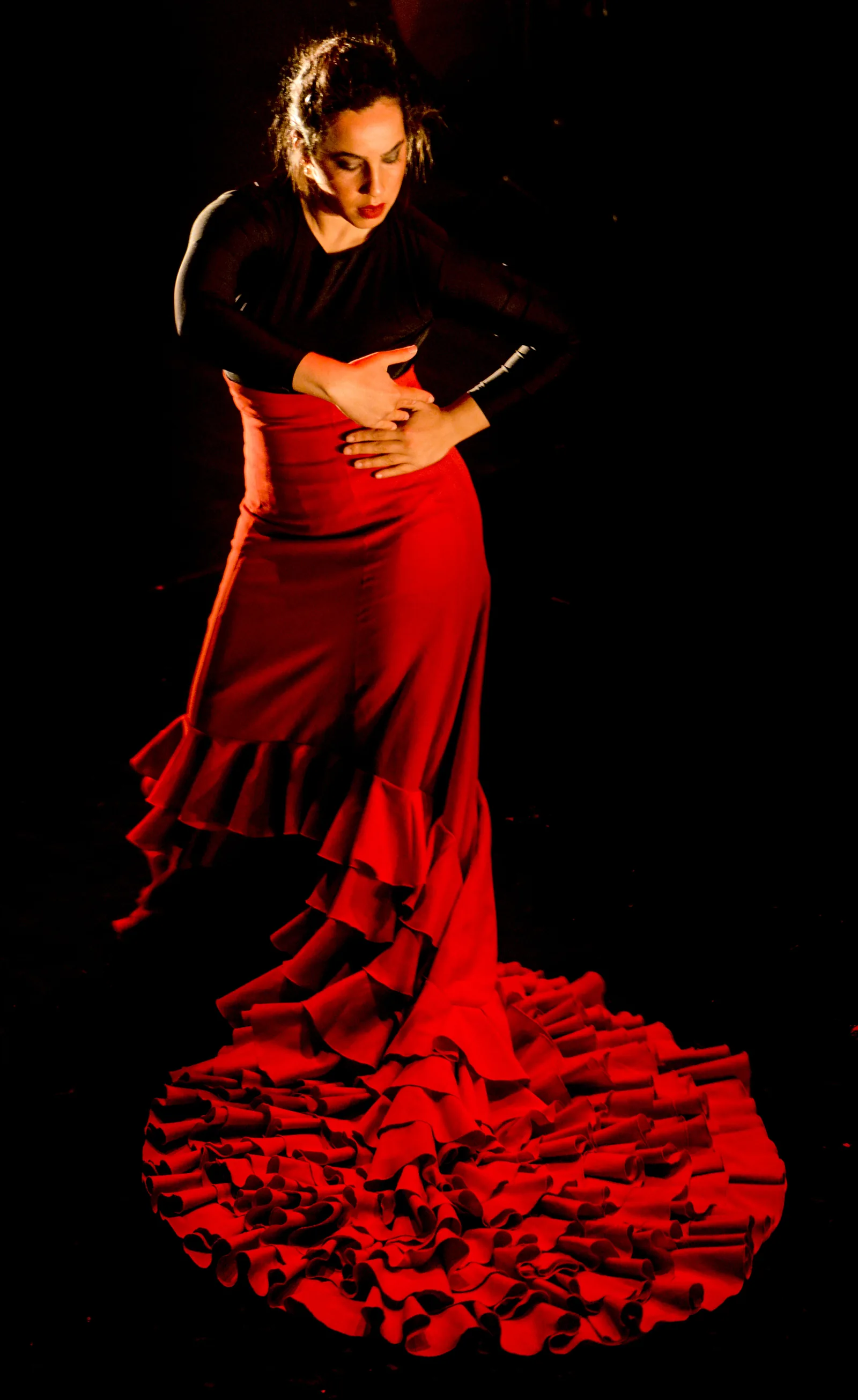 Solo flamenco dancer in red dress performing baile — UNESCO's 2010 inscription covers cante (song), baile (dance), and toque (guitar) as three interconnected elements of Spanish flamenco heritage