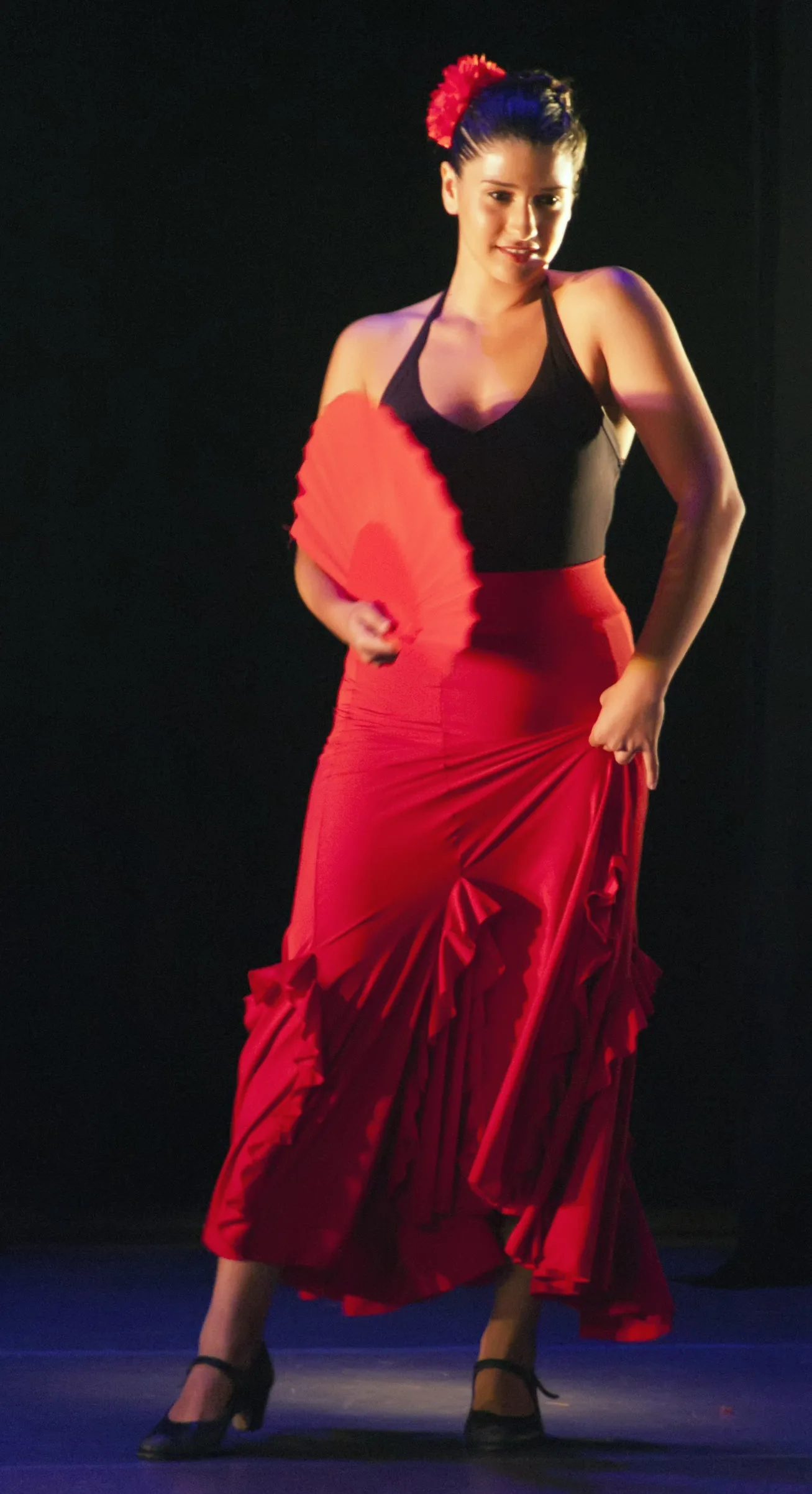 Flamenco dancer with red fan in traditional costume — one of over 50 palos (styles) recognized under UNESCO's 2010 inscription of flamenco as Intangible Cultural Heritage of Spain