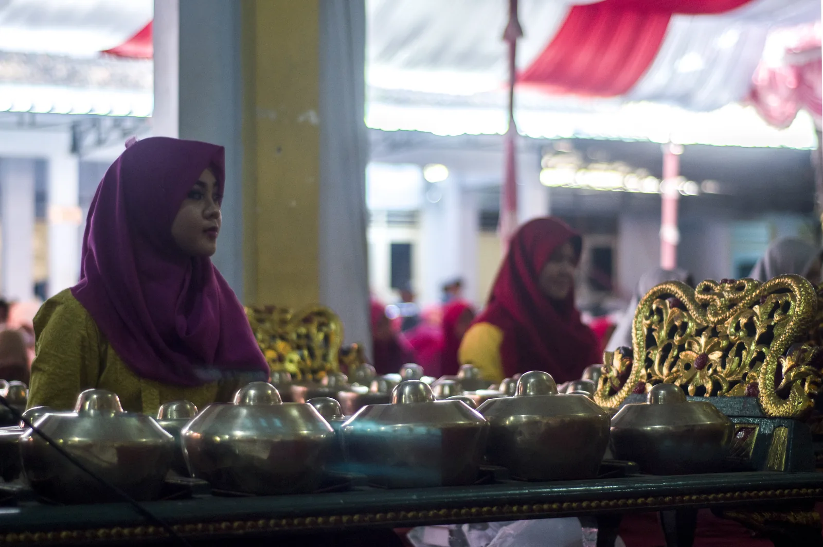 Female gamelan players seated before a row of bonang (gong-chime) instruments in an ornate Javanese gamelan setting during a wayang performance (Indonesia, August 2018) — gamelan's transmission across genders and communities is recognized in UNESCO's inscription of gamelan as intangible cultural heritage File 01607
