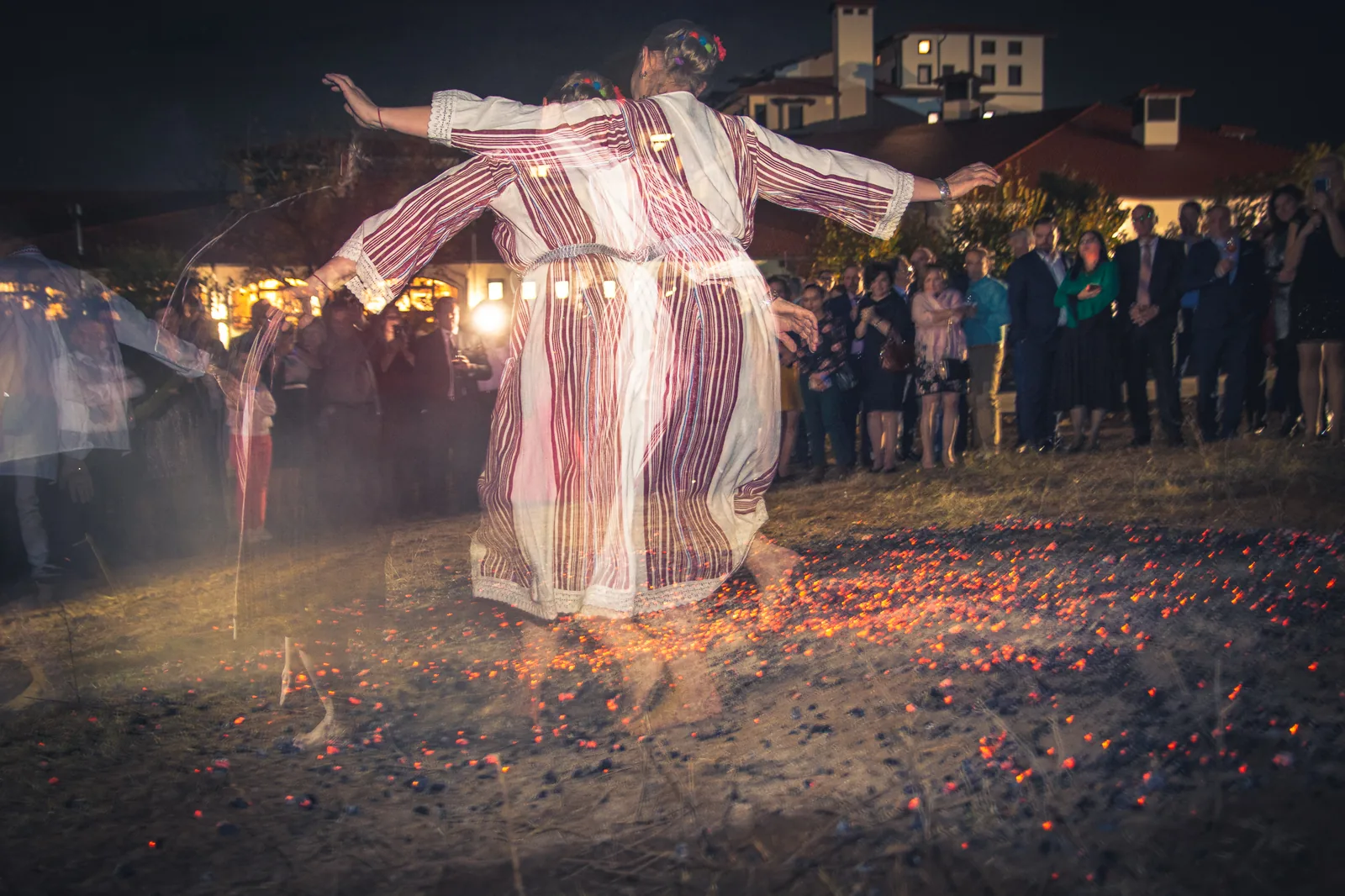 Woman in traditional Bulgarian embroidered dress dancing barefoot on glowing red embers at night with arms outstretched during Nestinarstvo fire-dancing ritual Strandzha Bulgaria — UNESCO Representative List Intangible Cultural Heritage of Humanity 2009