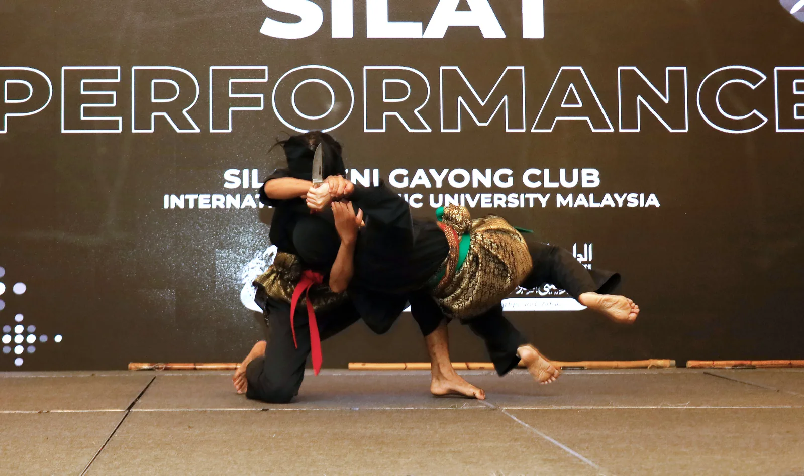 Two Silat Gayong practitioners in black traditional attire performing knife technique during Silat performance at ESEAP Conference 2024 Kota Kinabalu Malaysia — Silat UNESCO Representative List Intangible Cultural Heritage of Humanity File 01504