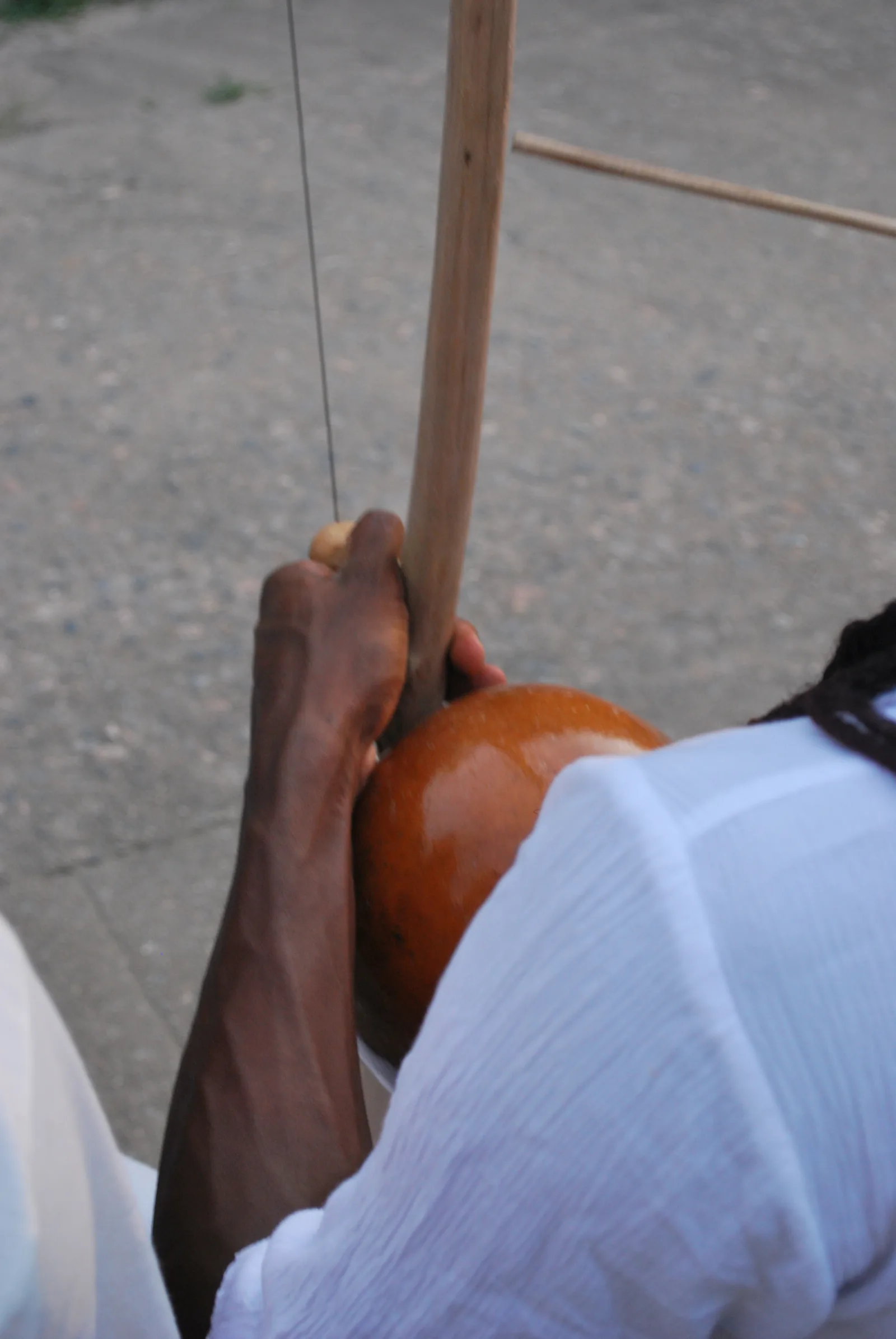 Close-up of a berimbau — the single-string musical bow central to capoeira performance — whose rhythmic signals warned enslaved practitioners of approaching overseers, embedding a system of coded resistance in the UNESCO ICH element File 00892, a tradition that reflects the broader pattern of cultural memory preserved under historical oppression