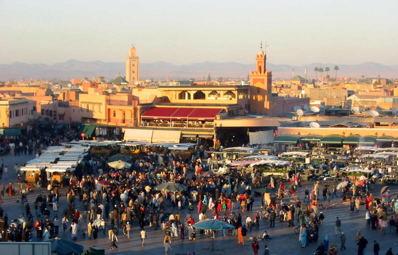 Evening view of Djemaa el-Fna square, Marrakesh, with the Koutoubia Mosque minaret and Atlas Mountains — the cultural space inscribed on UNESCO's Representative List of Intangible Heritage in 2008