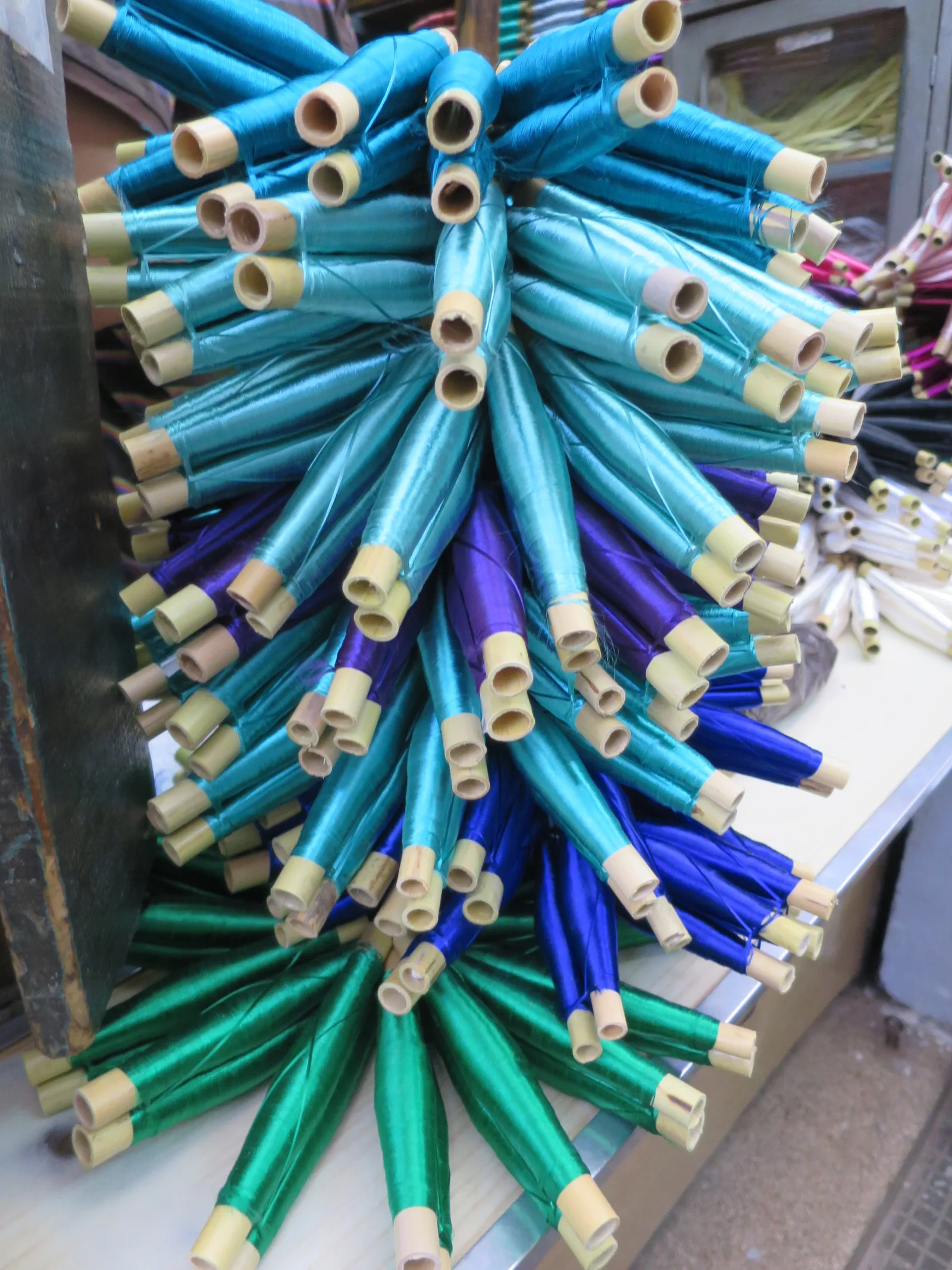 Reels of cactus silk threads in a Fez medina shop — the raw material for sfifa, the ornamental braid band woven from silk, gold, or silver threads and stitched along caftan edges, one of the two signature craft elements recognized in UNESCO's inscription of the Moroccan Caftan (File 02077, 2025)