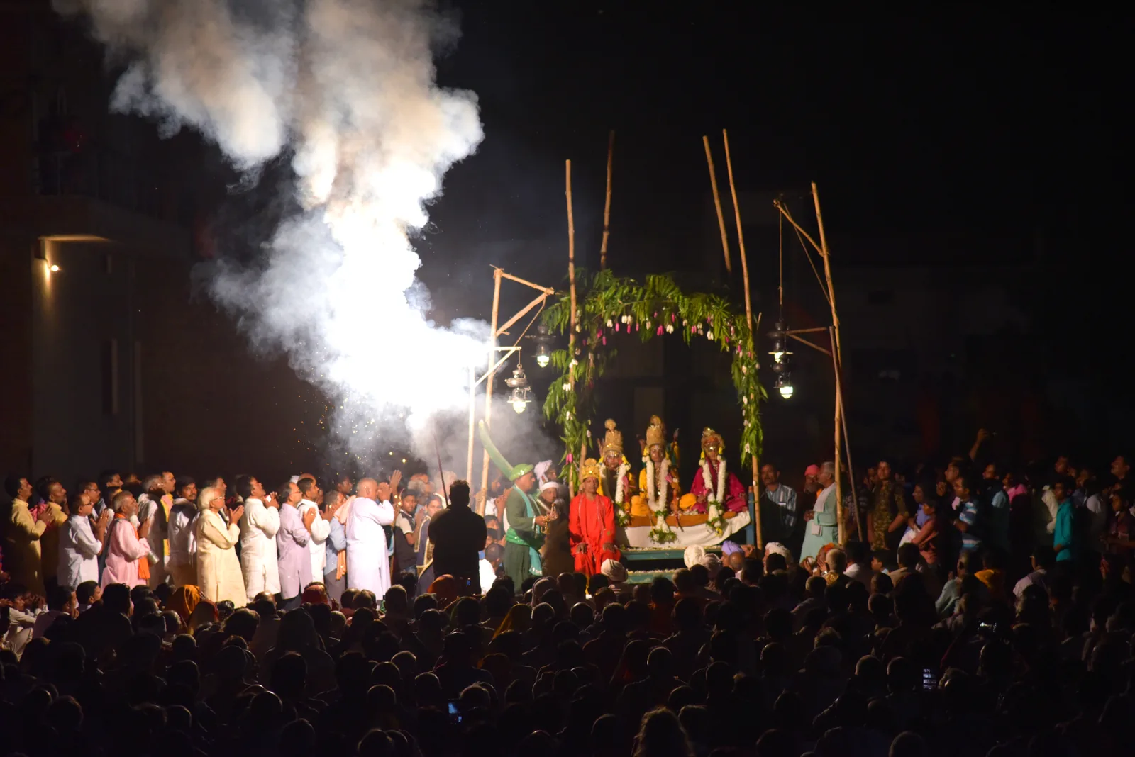 Nighttime Ramnagar Ramlila 2018 at Varanasi — a large crowd of devotees surrounds a decorated outdoor platform where Svarupas perform before fireworks illuminate the sky, showing the community scale of the 31-day UNESCO-inscribed Ramlila tradition patronized by the Maharaja of Kashi (Kashi Naresh)