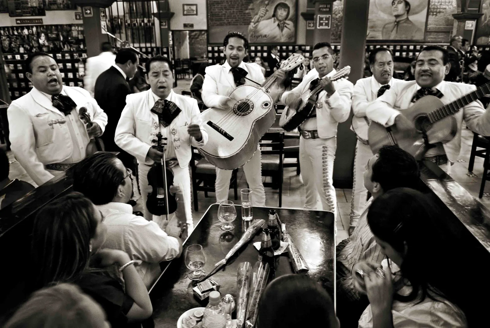 Mariachi ensemble in white charro suits playing vihuela and violin at Tenampa cantina in Mexico City's Plaza Garibaldi — UNESCO's 2011 inscription (File 00575) covers the ensemble tradition transmitted through family lineages and plaza apprenticeship in Guadalajara and Mexico City