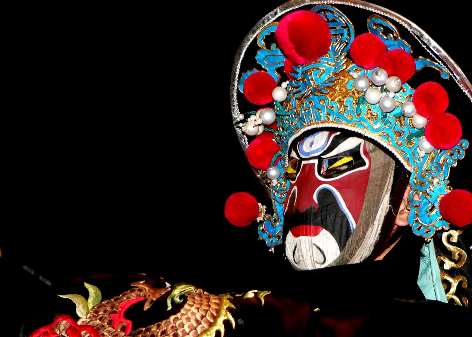 Close-up of Sichuan Opera bian lian (face-changing) mask with ornate traditional headdress — the red-black symbolic mask painting and rapid mechanical face changes are classified as juexue (skills of rare excellence)