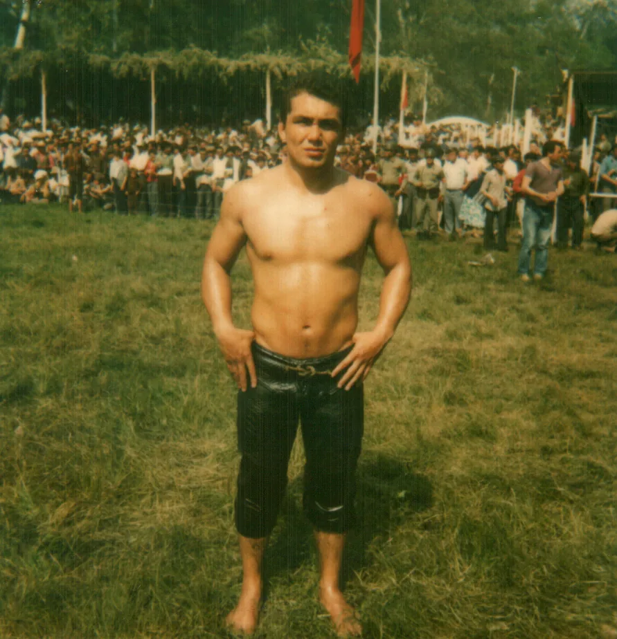 Turkish oil wrestling pehlivan (wrestler) in traditional leather kıspet at a festival with crowd — Kırkpınar oil wrestling is inscribed on UNESCO's Representative List as File No. 00386, documented since 1346 CE