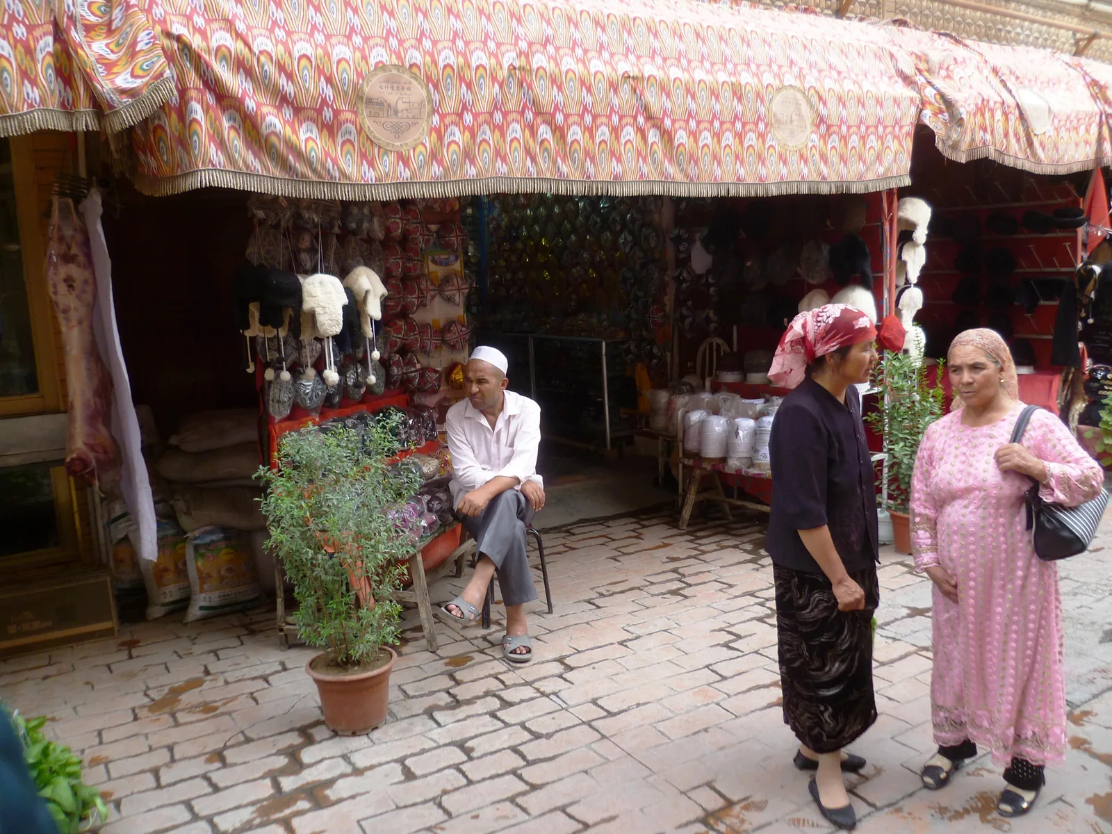 Uyghur residents in traditional dress at a market stall in Kashgar Old City's bazaar, Xinjiang — Kashgar is one of the main oasis cities of the Silk Road Tarim Basin where the Twelve Muqam (On Ikki Muqam) developed, as documented in UNESCO's inscription of Uyghur Muqam of Xinjiang as Intangible Cultural Heritage File 00109
