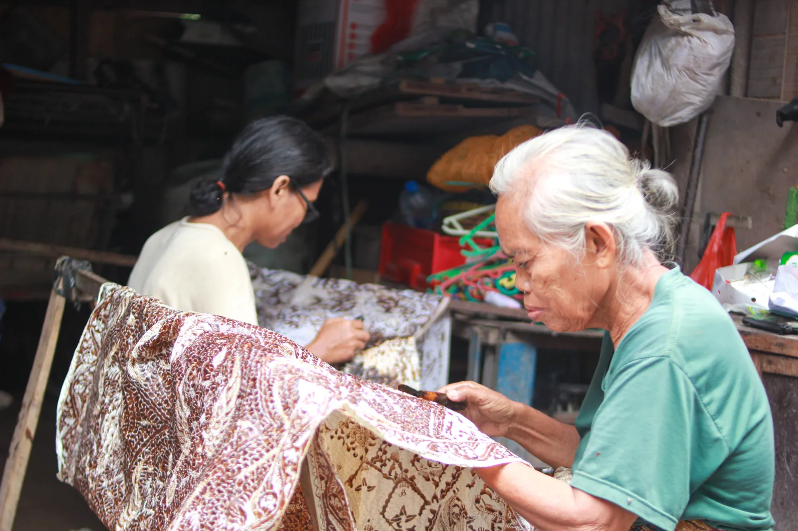 Mother and daughter practicing batik tulis in Trusmi, Cirebon, Indonesia (2026) — intergenerational transmission of Indonesian batik craft, inscribed on UNESCO's Representative List as traditional craftsmanship domain under the 2003 Convention for the Safeguarding of the Intangible Cultural Heritage